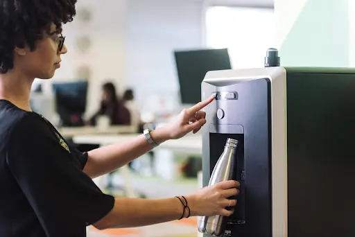 Mujer usando una máquina dispensadora de agua