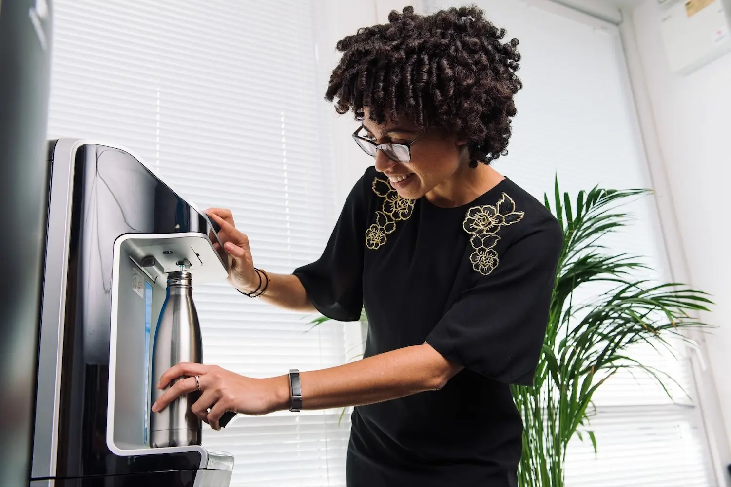 Mujer bebiendo agua de una máquina dispensadora de agua