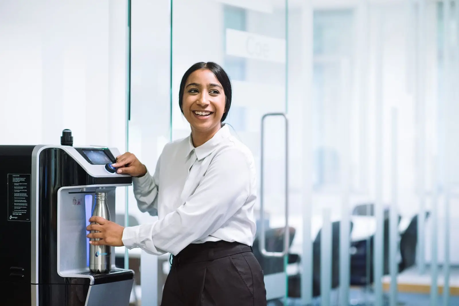 Mujer embotellando agua de máquina dispensadora de agua